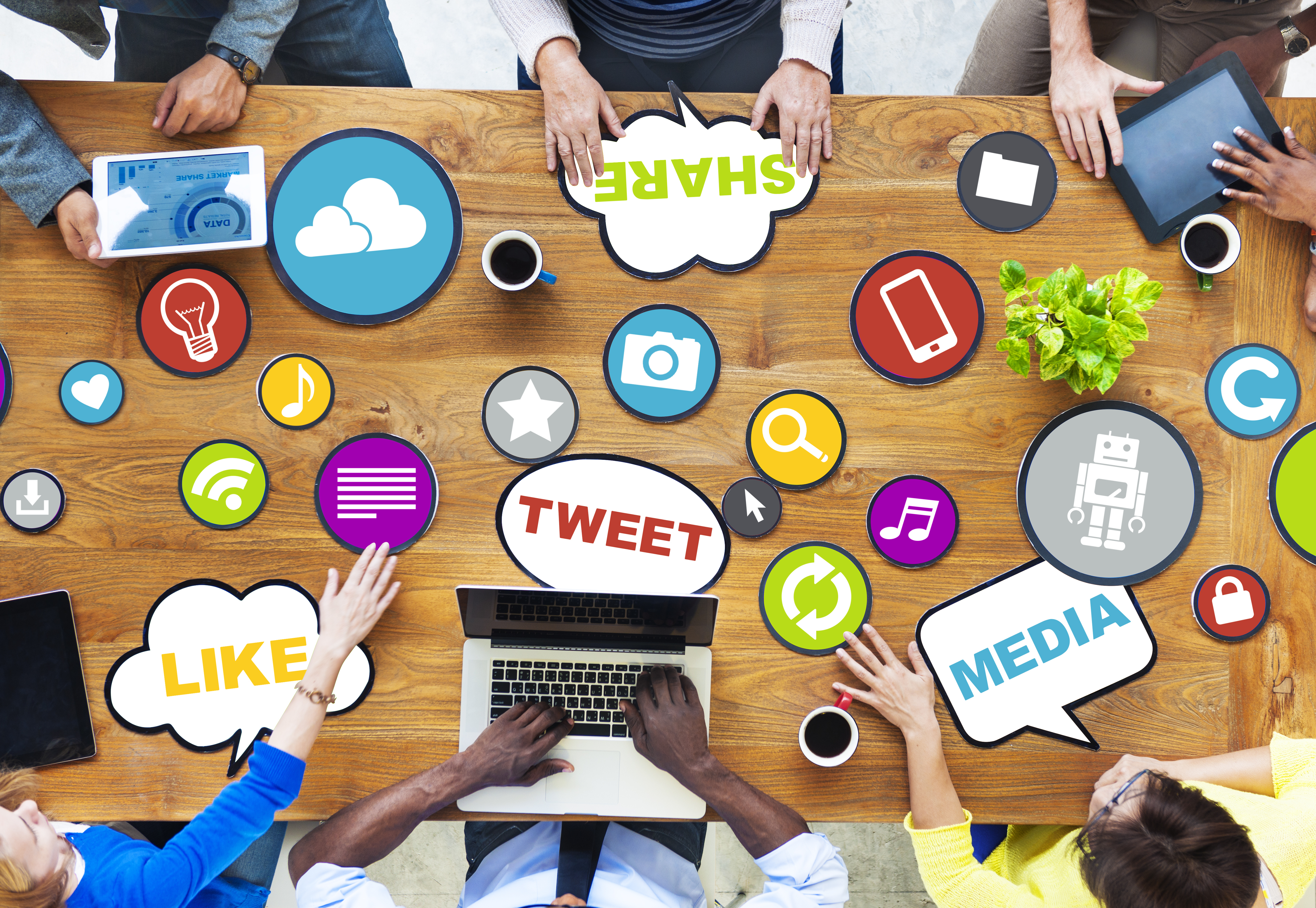 A table with various social media images laid out with employees hands holding some around the table